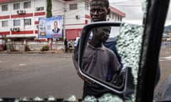 Men try to fix a car that had its windows smashed and tyres slashed outside the APC headquarters in Freetown on 26 June.