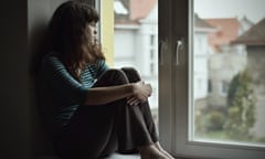 Sad young woman sitting by a window 