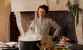film still of a woman in 19th century clothes standing in a period kitchen behind a steaming pot