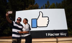 people pose for a selfie in front of the Facebook “like” sign at Facebook’s corporate headquarters in Menlo Park, California. 