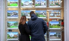 A couple look at houses for sale in the window of William H Brown estate agents in this arranged photograph in Chelmsford