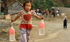 A girl carries bottles of water fetched from a mountain spring in China’s Guizhou province