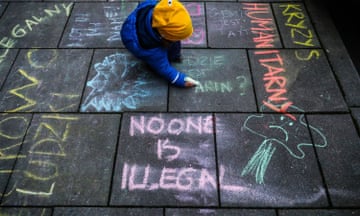 A person writes slogans on the pavement in Kraków during a protest against the Polish government’s treatment of migrants.
