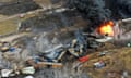 Debris from a Norfolk Southern freight train lies scattered and burning along the tracks