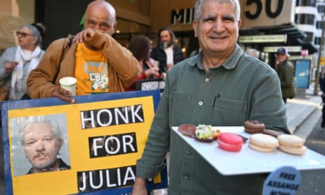A man offers sweets to Julian Assange supporters.