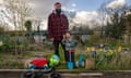 Azeem Choudhry and Ibrahim standing on their plot. Ibrahim is holding a child's spade, and his bike is in the foreground