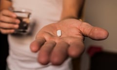 A man holds a pill and a glass of water