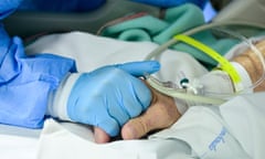 A hospital medic holds the hand of a coronavirus patient.