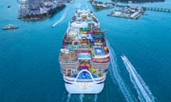 A huge ship, with hundreds of crew members seen as tiny figures on the many decks, approaching a US city