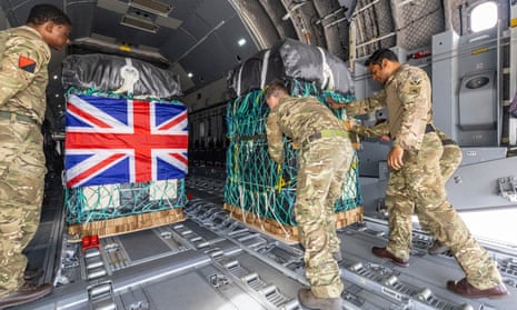 British army personnel load humanitarian aid on to a plane with a union jack on one of the crates