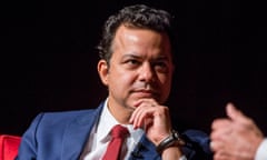 man in a suit and red tie listening to an unseen speaker