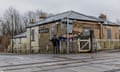 People stand in front of historic brick building behind railway tracks