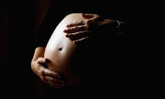 a pregnant woman holds her stomach.