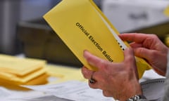 Older white female hands open a yellow envelope.