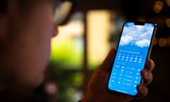 A man looks at his mobile device running the iOS Apple weather app