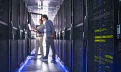 Technicians standing between rows of computers in a datacentre