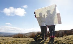 Two hikers on top of a hill, looking at map.