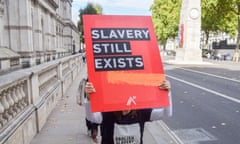 Placard reading Slavery still exists being carried down Whitehall in London