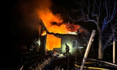 A firefighter in front of a house that is on fire