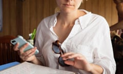 A woman reading the menu in a restaurant with a smartphone in her hand