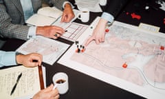 The hands of war-gamers sitting around a table with maps on it