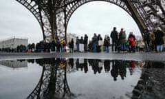 Visitors queue beneath the Eiffel Tower, in front of a flooded area, on the day it has reopened after a strike