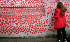 A member of the public writes a  message on the Covid memorial wall in London