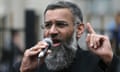 Anjem Choudary, who has grey hair and a grey beard, speaking while holding a microphone in 2015