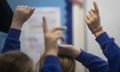 Children with raised hands in a classroom