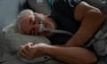 Older man asleep in bed wearing a cpap machine mask