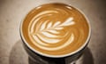 Pretty latte art of a flower in the foam on the top of a cup of coffee.