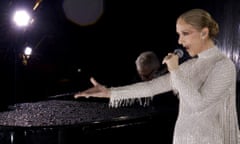 Céline Dion in an evening dress holding a microphone in her left hand and with her right arm extended