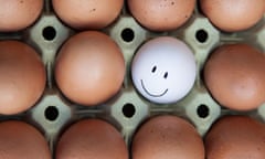 Single white egg with happy faces surrounded by blank brown eggs.