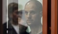 Headshot of Evan Gershkovich in the glass-covered defendants’ box