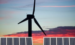 A wind turbine in front of solar panels