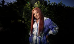 Jessica Mauboy in front of some bushes on a sunny day