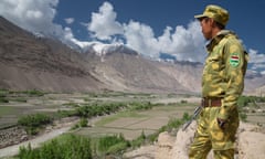 Soldier, in profile, looks out across valley with mountains in the distance