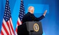 Joe Biden waves as he turns away from a podium with US flags in the background.