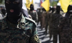 Columns of men wearing balaclavas and camouflage military fatigues march with flags