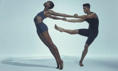 A woman dancer leans back with her arms held by a male dancer, who has his leg raised and pointed at her