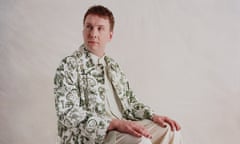 Joe Lycett sitting down,wearing green patterned jacket
