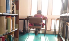 Rear view of a student sitting at a desk studying in the library, Llanbadarn campus, Aberystwyth University.