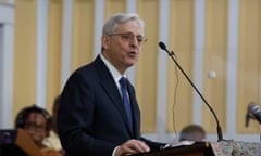 Man wearing glasses and suit at podium in front of microphone