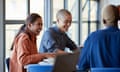 Cheerful young woman studying with male friends at desk in university classroom