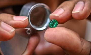 A person examines a green emerald