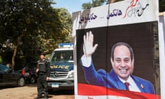 An Egyptian police officer stands guard outside a polling station with an electoral banner depicting incumbent Abdel Fatah al-Sisi during elections in March.
