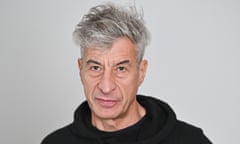 Man wearing black top poses in front of gray background