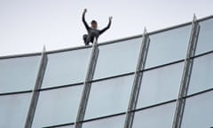 Alain Robert waves after climbing the Skyper building in Frankfurt, Germany, in September 2019.