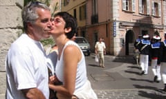 A woman kisses a man on a sunny cobbled European street.