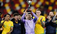 Socceroos captain Mat Ryan lifts the Trans-Tasman Trophy after Australia beat New Zealand at Gtech Community Stadium in Brentford.